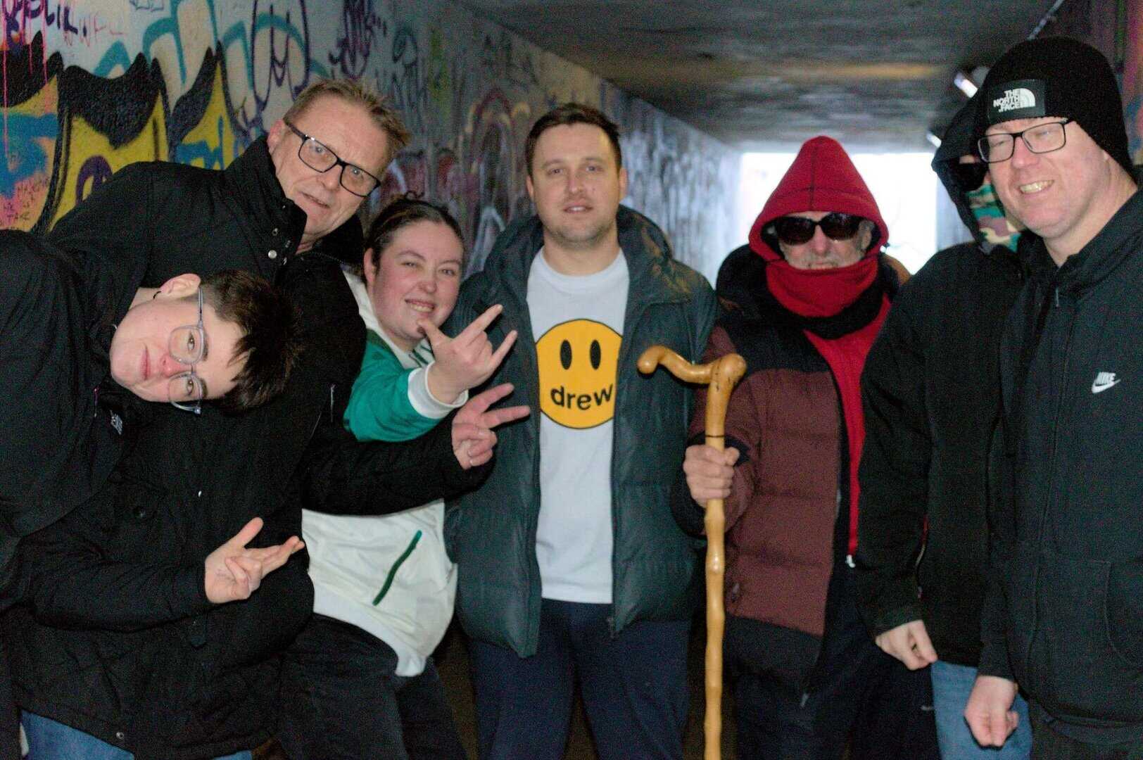 Group of diverse people in an urban tunnel, supporting recovery efforts.