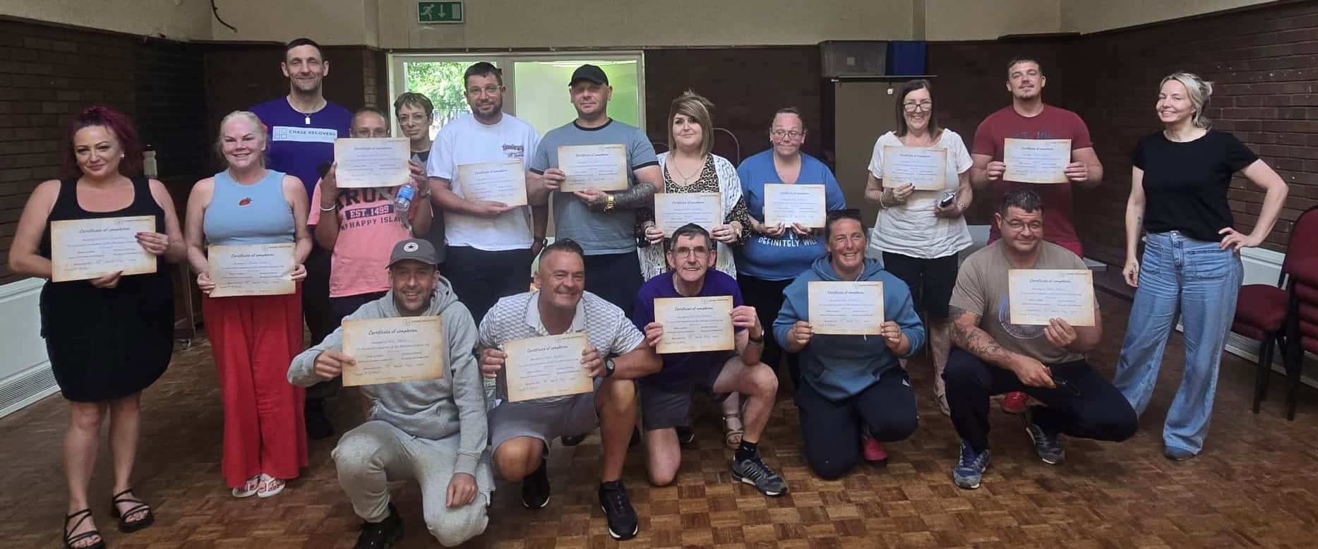 Group of diverse individuals holding certificates after completing recovery programme at Chase Recov.