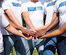 Group of volunteers joining hands during training session at Chase Recovery.